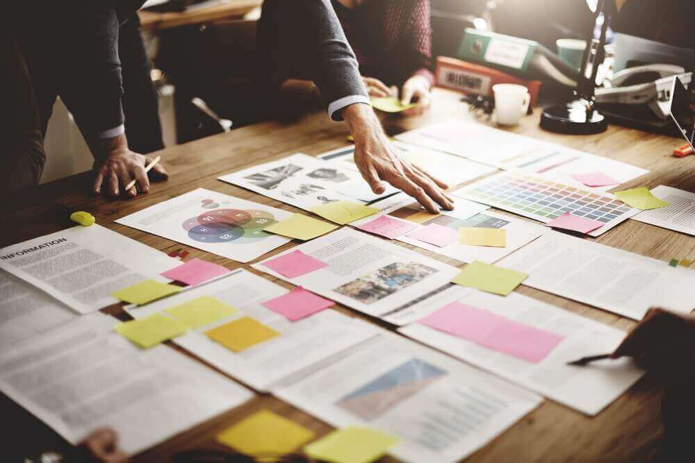 Man in suit working on a desk with a lot of papersheets and post its